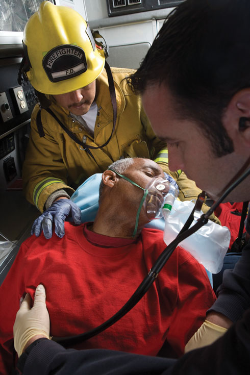 Firefighter and paramedic helping man in ambulance